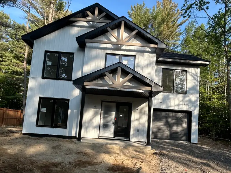 Maison de deux étages blanche avec pignons décoratifs en bois
