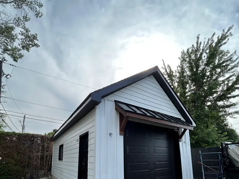 Garage détaché avec revêtement blanc et porte de garage noire
