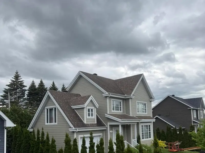 Maison de deux étages avec revêtement gris-vert et pignons