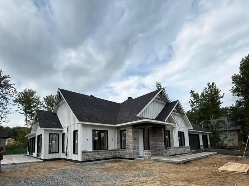 Maison blanche avec pignons, toiture noire et base en pierre